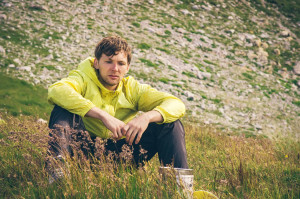 Man relaxing in mountains sitting on grass valley Traveling hiking summer recreation